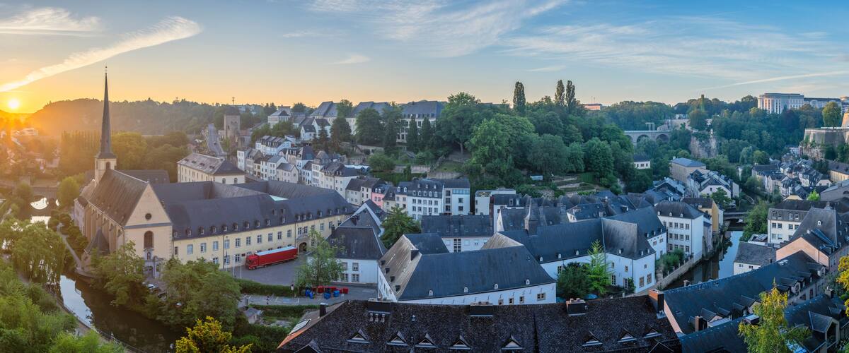 A historic town with a river, a prominent church, and a castle in the background.