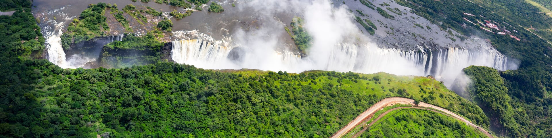 Seen from the air the mighty Zambezi River stretching wide upstream plummets into a dramatic gorge, creating one of the largest waterfalls in the world, Victoria Falls