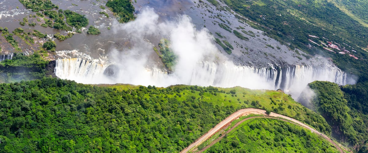 A large waterfall cascading down a lush green hillside, surrounded by dense forest.