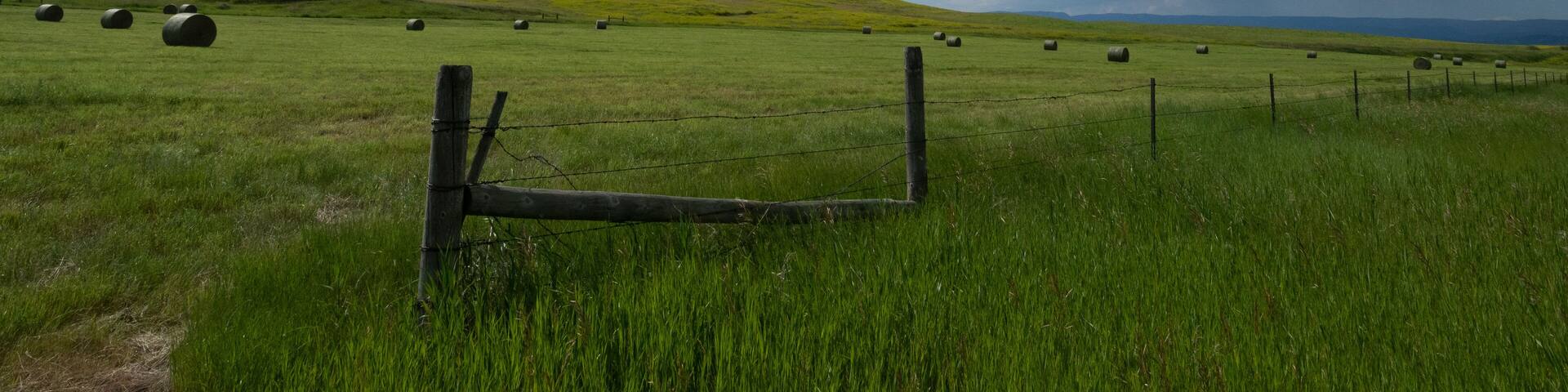 Dramatic Storm Clouds Above a Green Pasture with Hay Bales
