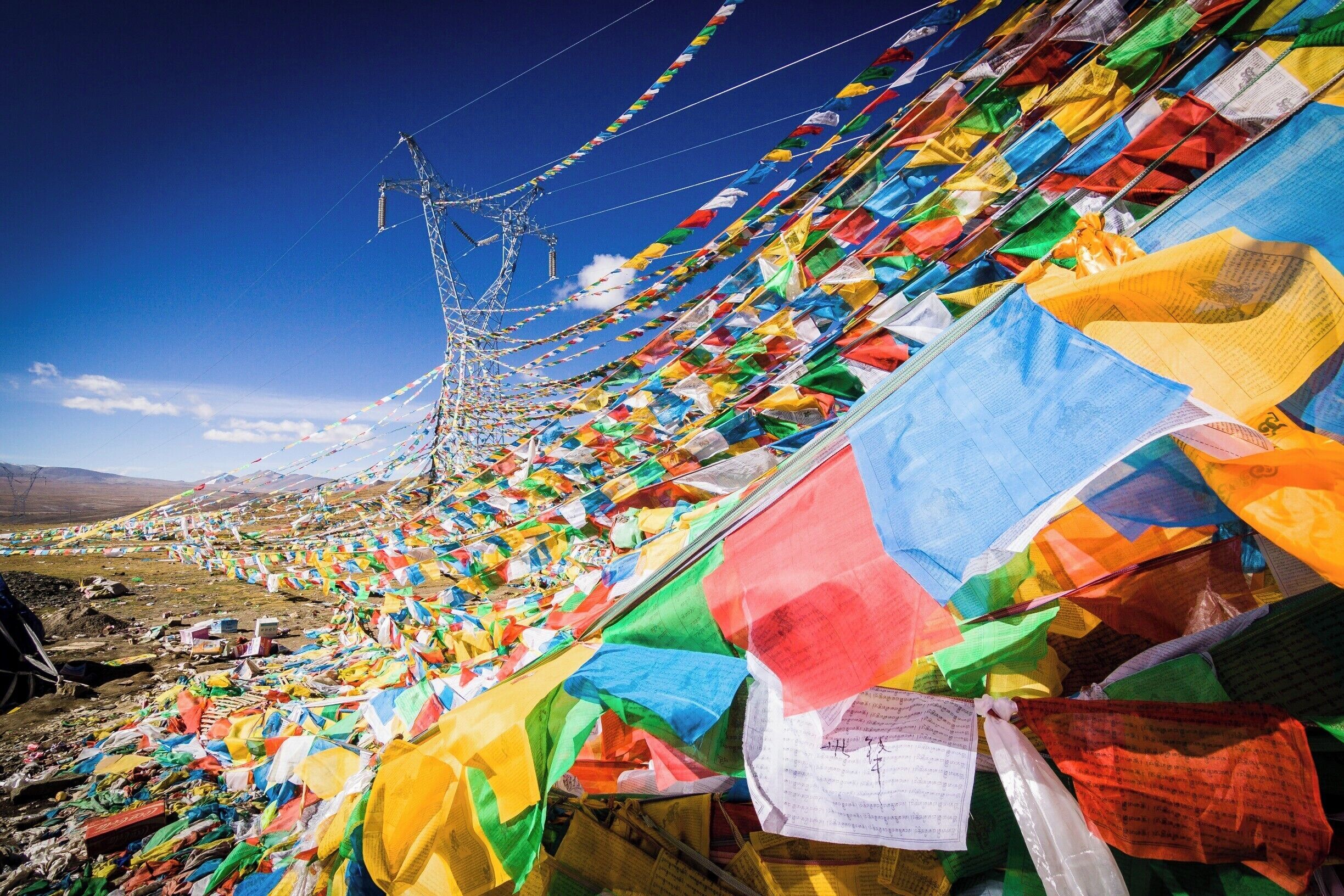 A line of colorful prayer flags stretching across a mountainous landscape.