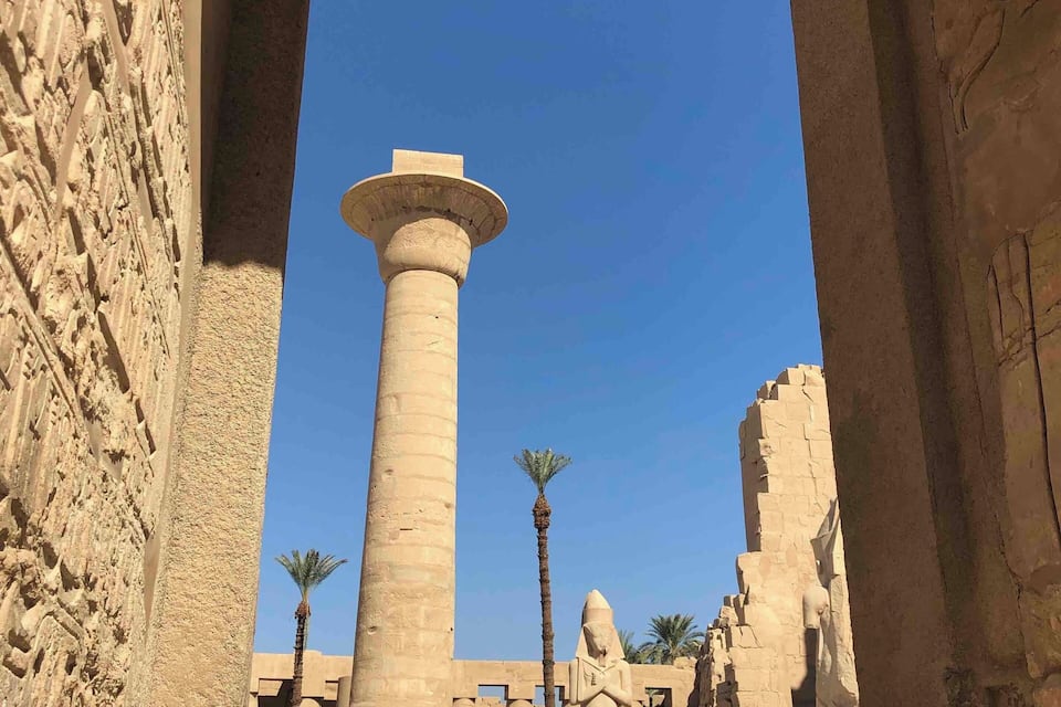 Un templo egipcio antiguo con grandes columnas de piedra y un cielo azul brillante.
