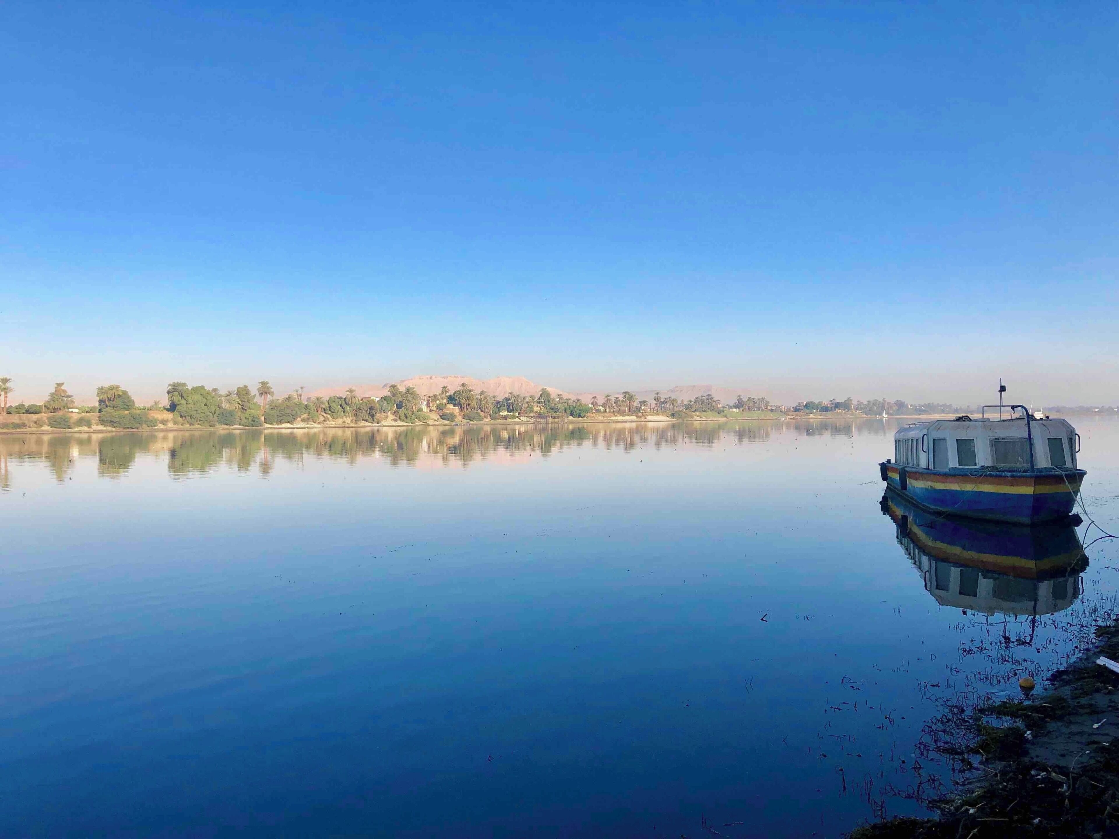 A calm lake with a small boat docked on the right.