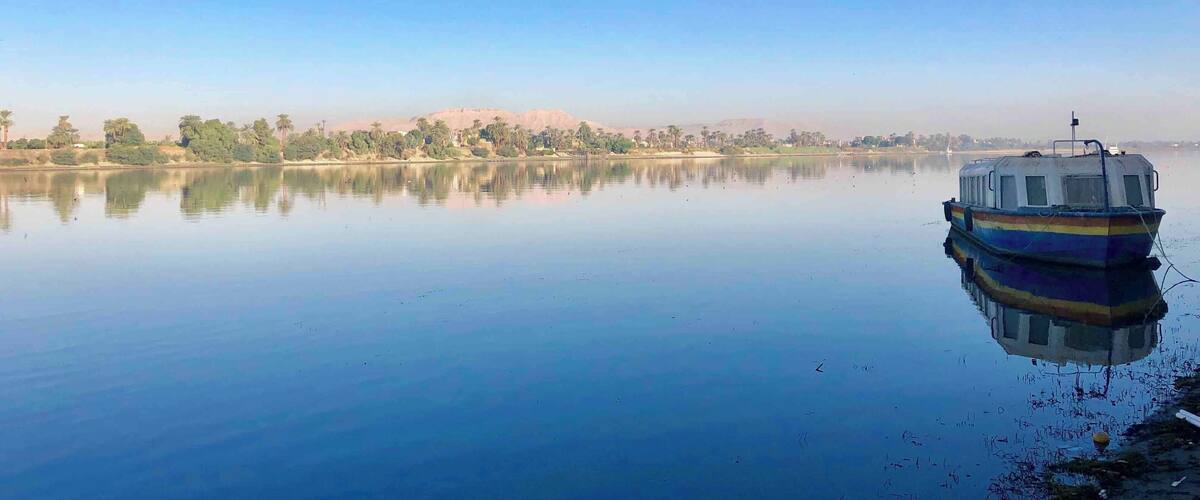 A calm lake with a small boat docked on the right.
