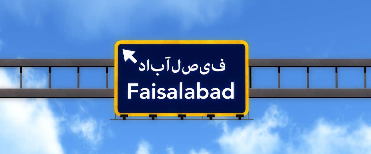 A road sign with the text "Faisalabad" and an arrow pointing left.