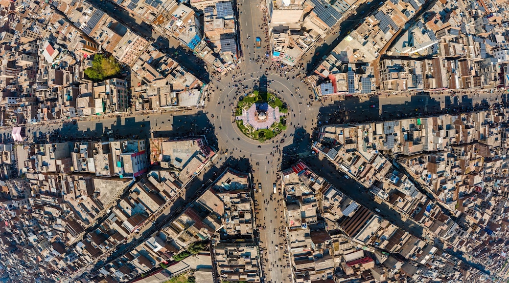 A bird's-eye view of a densely packed urban area with a central roundabout, numerous buildings, and a grid of streets.