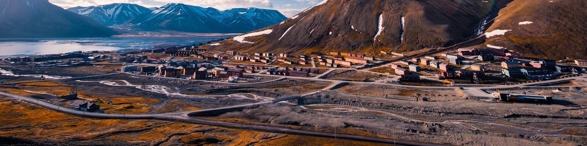 A town nestled between mountains with a clear sky and a river in the background.
