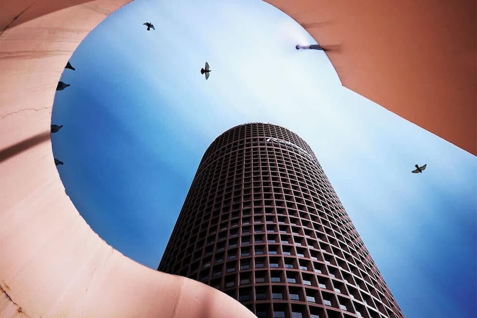 A tall building with a curved facade and a clear blue sky above.