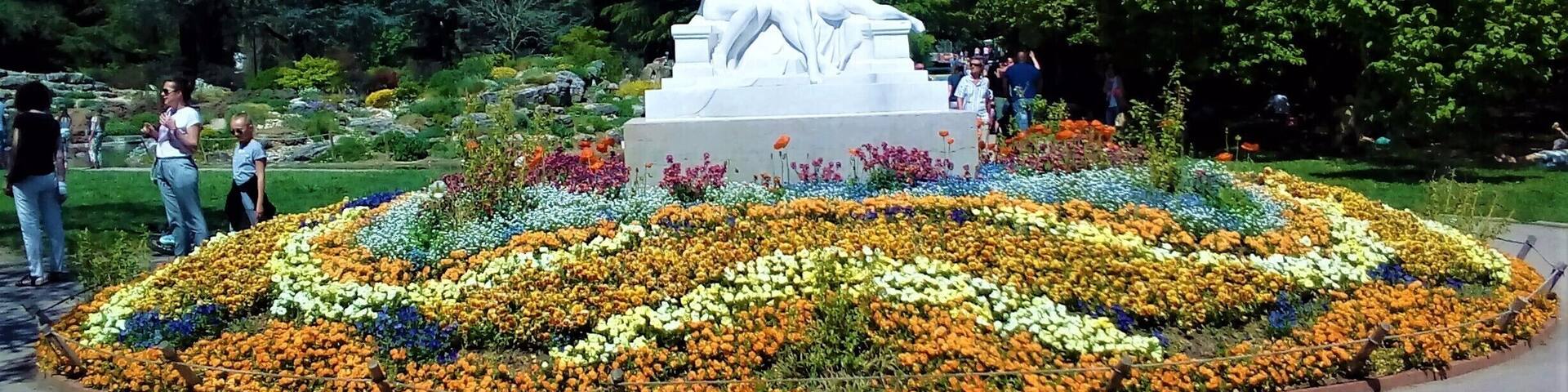 A statue surrounded by a circular flower garden with various colors.
