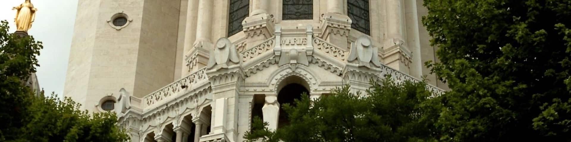 A grand cathedral with ornate architecture, two towers, and a statue on top.