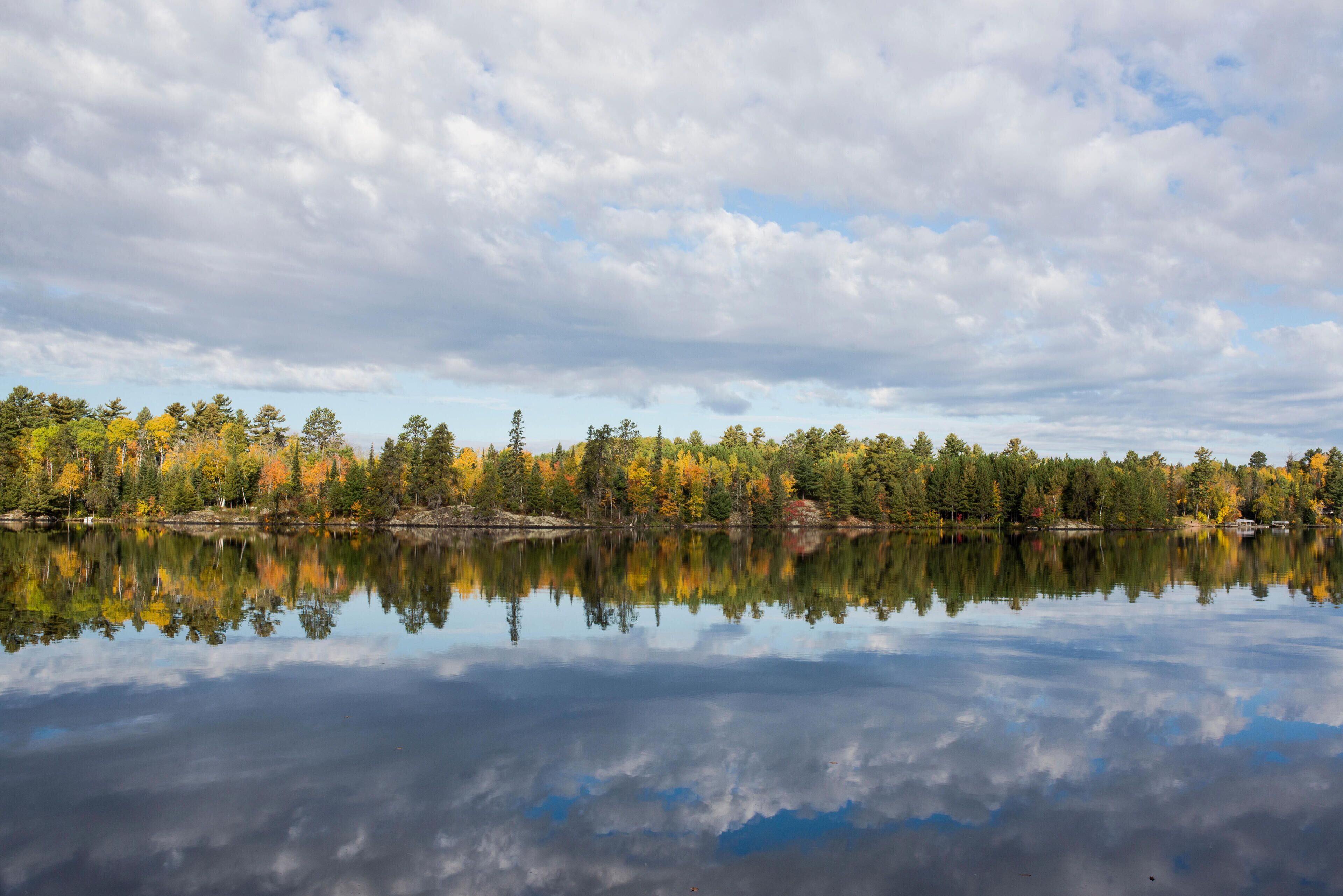HM6T3R Scenic view of trees and cloudy sky reflecting on calm lake during autumn