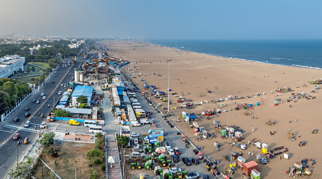 Un paysage urbain côtier avec une plage animée, une autoroute et des bâtiments industriels.