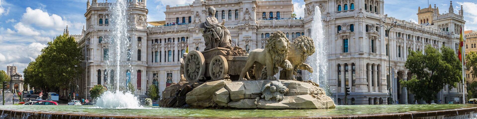 A grand building with a central tower, a fountain with lions, and a clear blue sky.