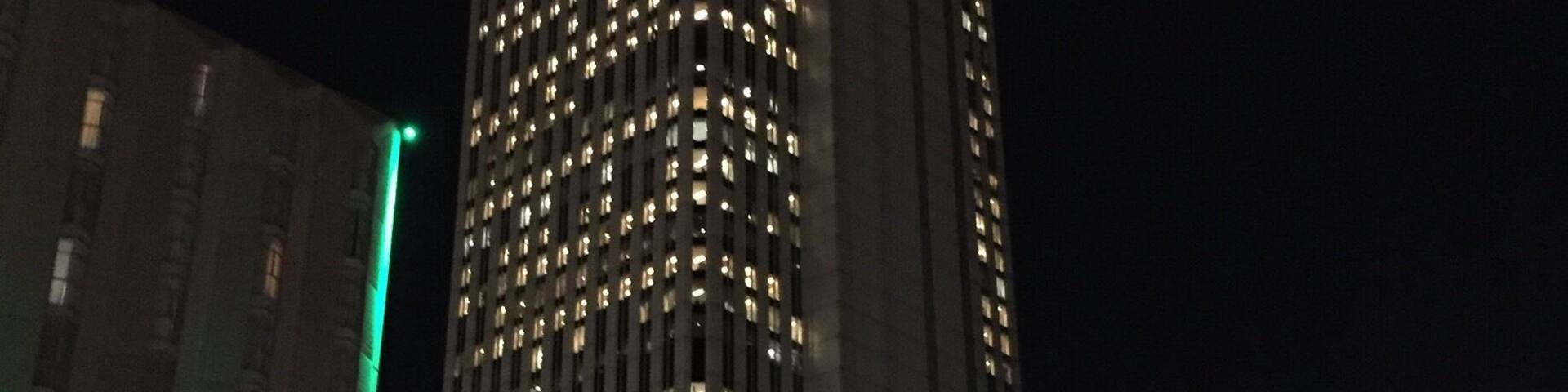 Un edificio alto con numerosas ventanas iluminadas de noche.