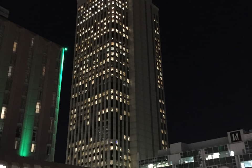 Un edifici alt amb moltes finestres il·luminades durant la nit.