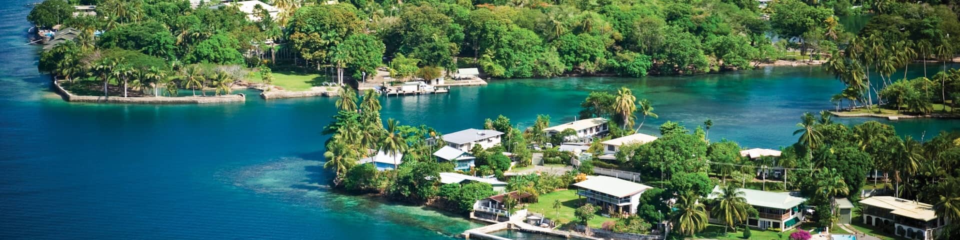 A tropical island with clear turquoise waters, dense greenery, and a lighthouse.