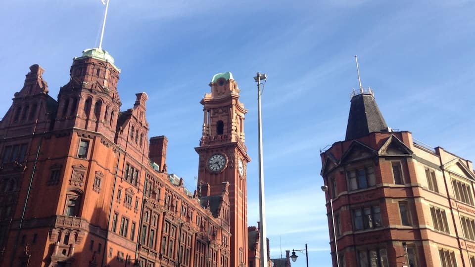 A historic building with a clock tower and a flagpole.