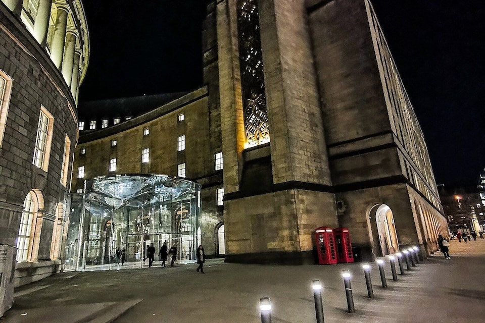 Un edificio storico con un'imponente torre centrale e un ingresso in vetro.