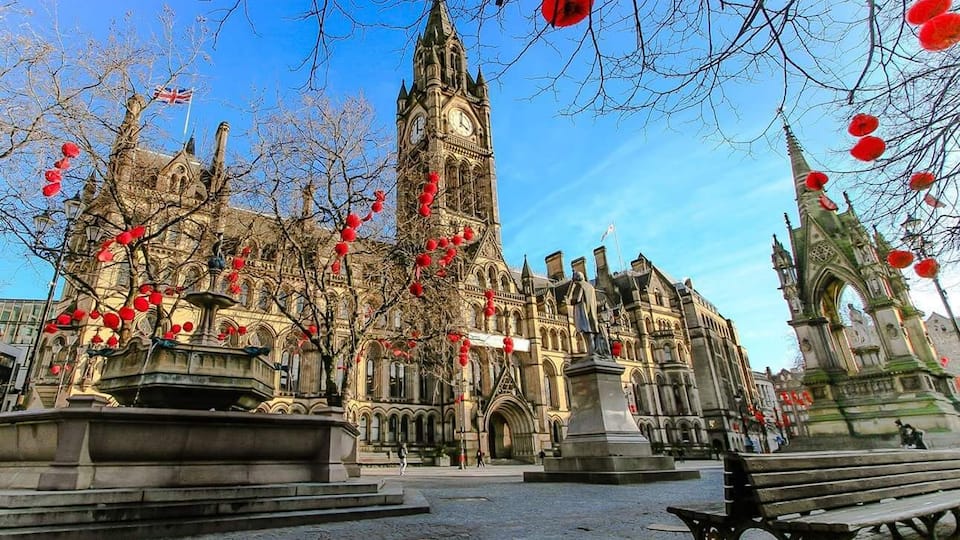 A historic building with a clock tower, a fountain, and red lanterns.