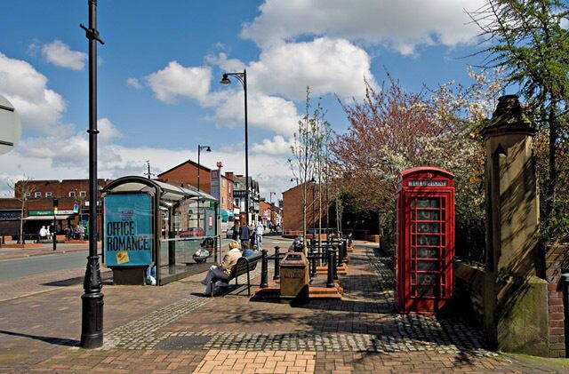 A red telephone booth, a blue office romance sign, and a brick sidewalk.