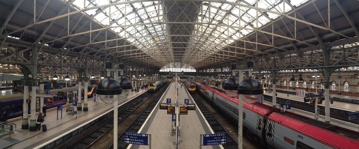 Una amplia estación de tren con varias vías y andenes, que cuenta con una estructura de techo alta y abovedada.