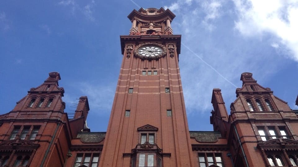 A tall brick tower with a clock and the word "PATACH" on top.