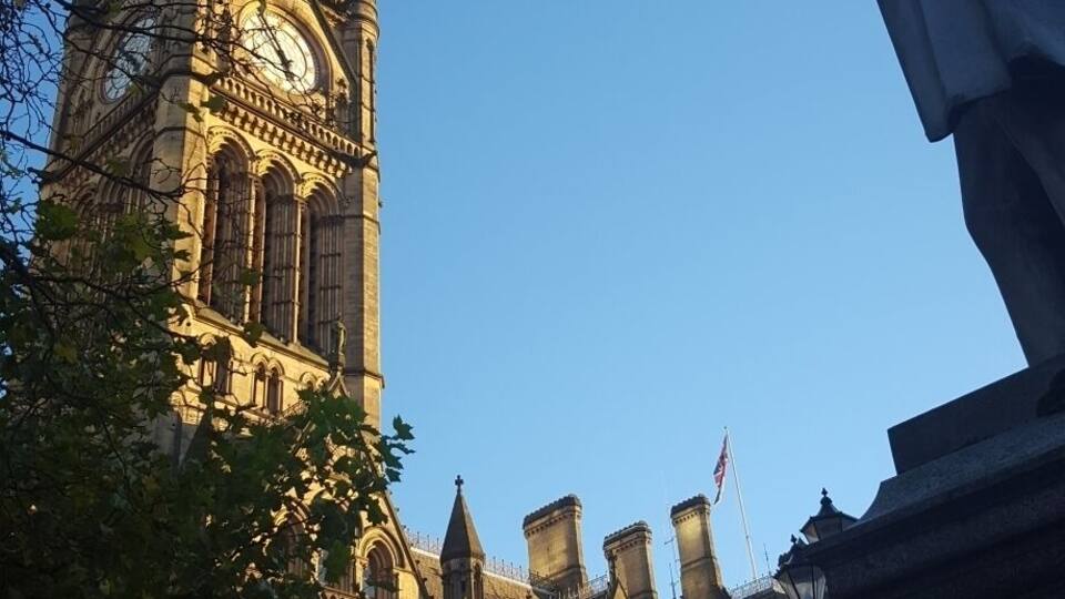 A historic building with a clock tower and a statue.