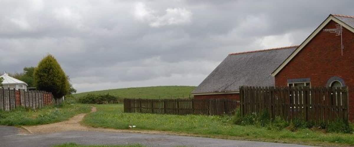 A rural road with a brick barn and wooden fence.
