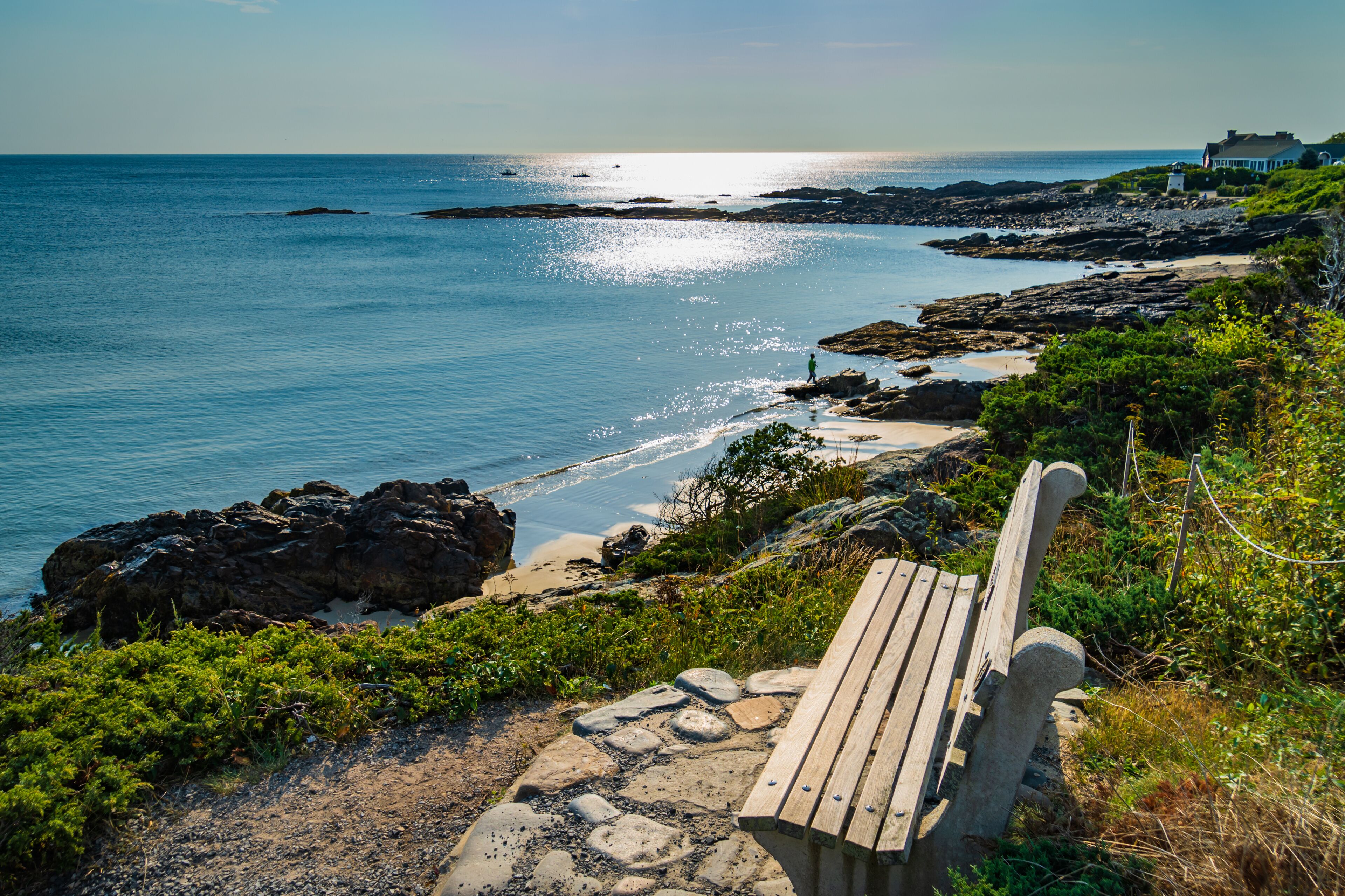 A wooden bench overlooking a rocky shoreline with the ocean in the background.