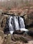 Ein Wasserfall stürzt über Felsen in einem bewaldeten Gebiet.