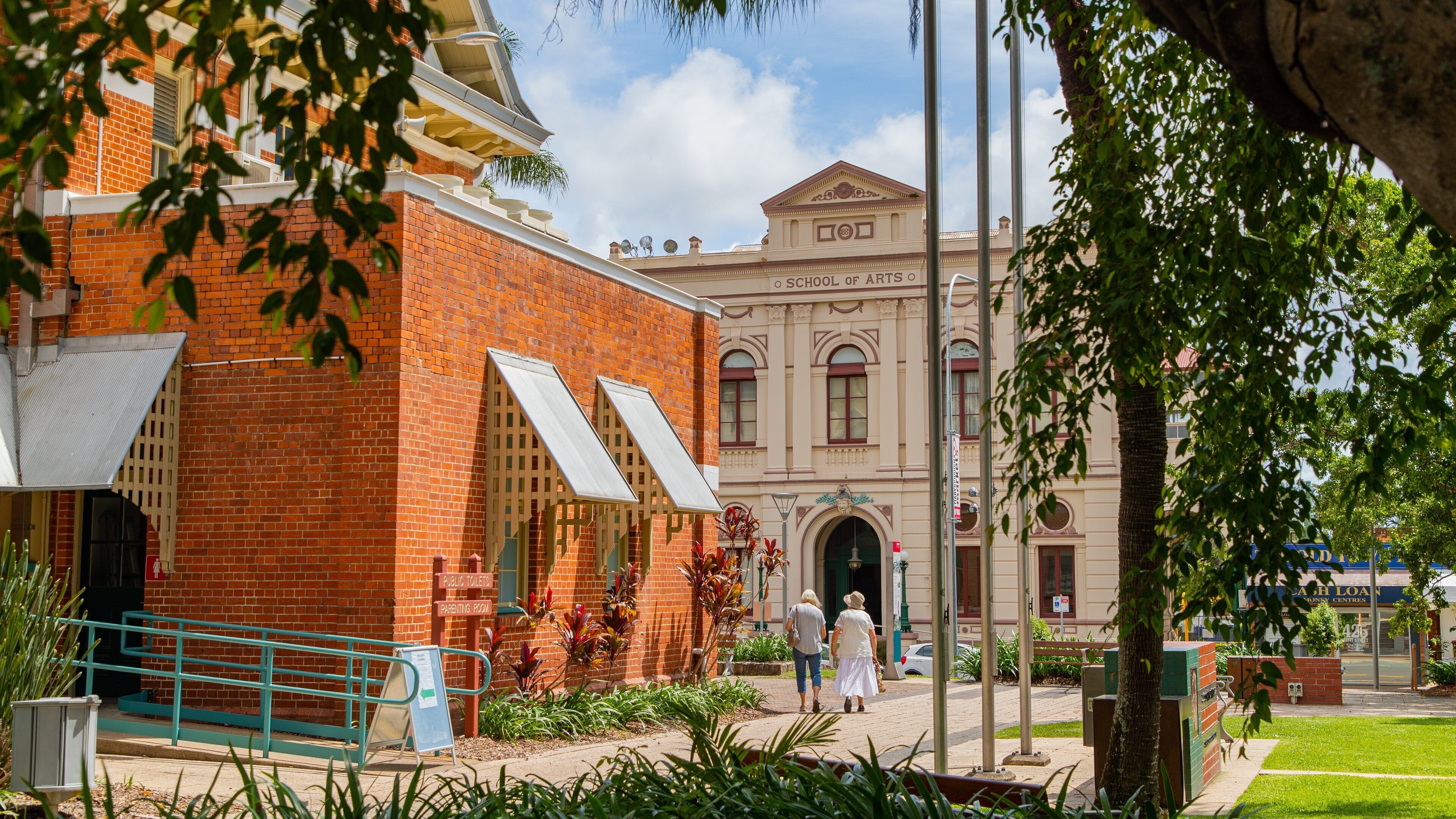 A red brick building with a white awning, a sign for public toilets, and a sign for a parenting room.