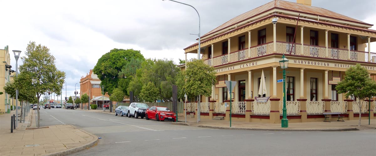 A street with a heritage center building, cars parked along the side, and trees lining the road.