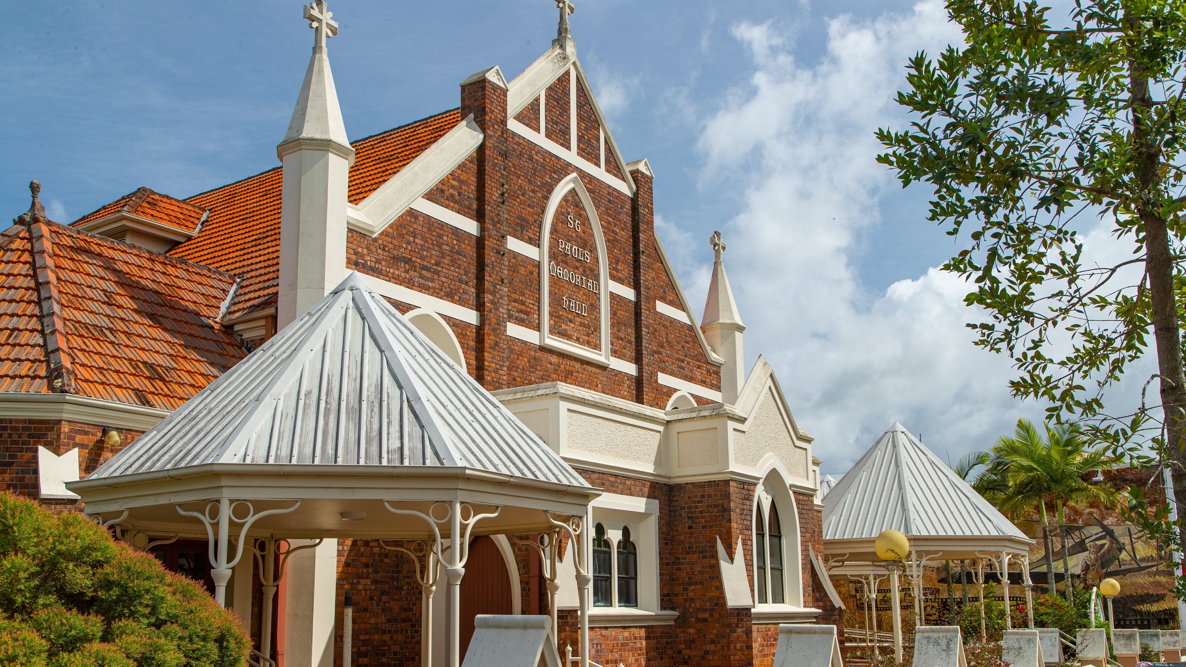 A church with a red-tiled roof, white spires, and a cross on top.