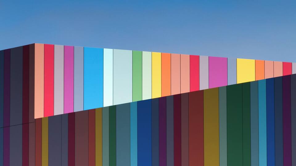 Une structure colorée, à rayures, se détachant sur un ciel bleu clair.