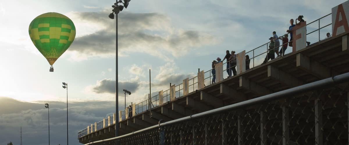 A hot air balloon, a bridge, and people on the bridge.