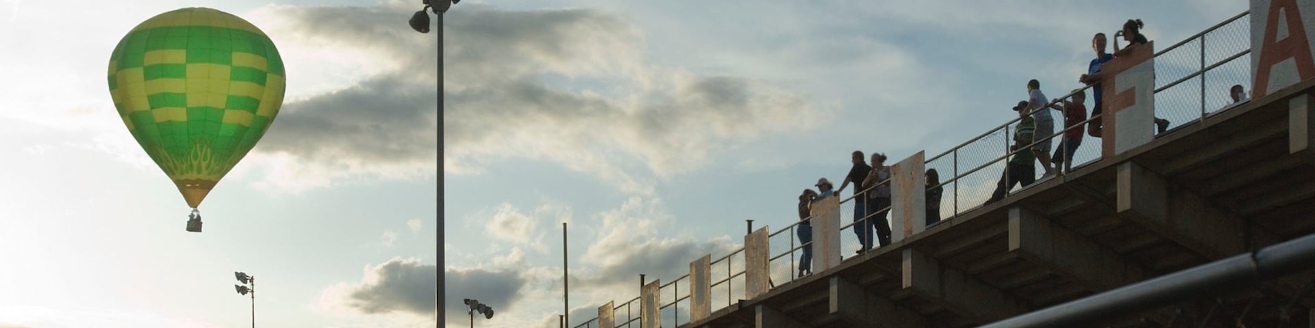 A hot air balloon, a bridge, and people on the bridge.