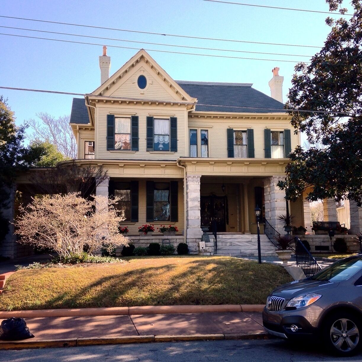 A two-story house with a gabled roof, green shutters, and a front porch.