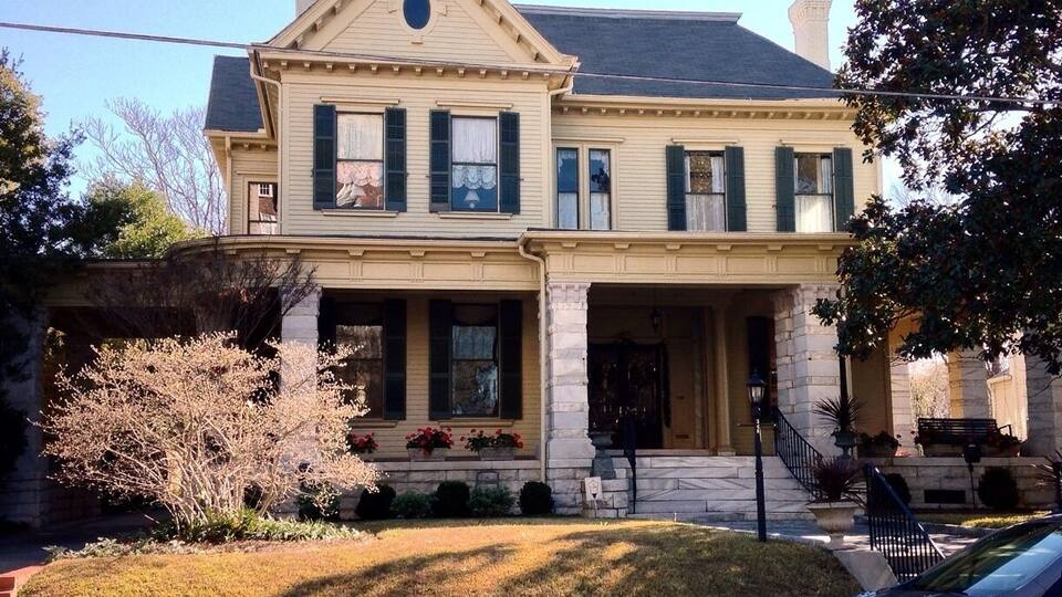 A two-story house with a gabled roof, green shutters, and a front porch.
