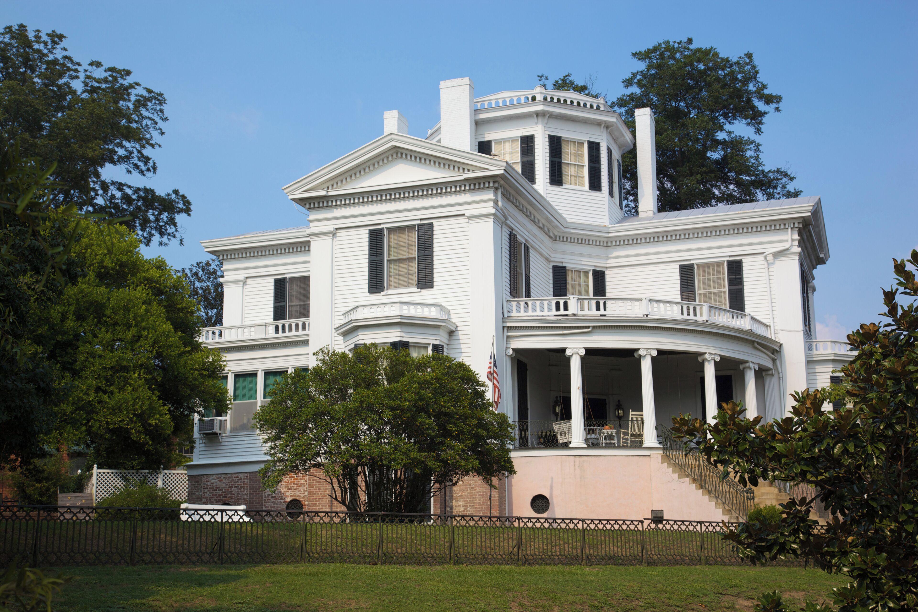 A large white house with a wrap-around porch and columns.