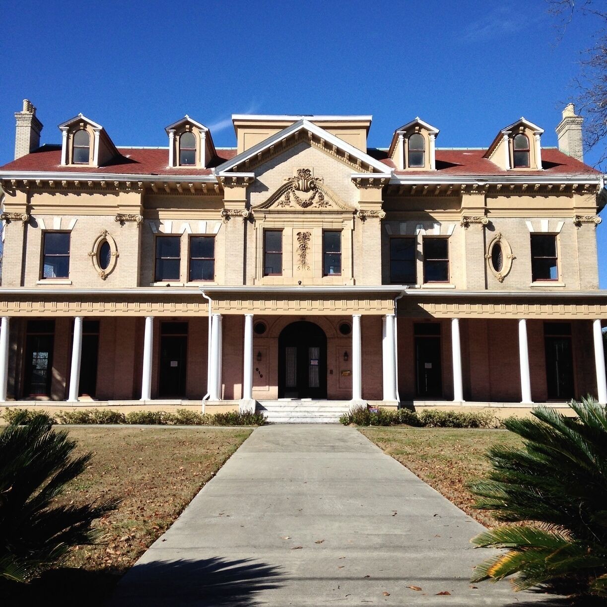 A large, historic building with a symmetrical facade, central pediment, and multiple windows.