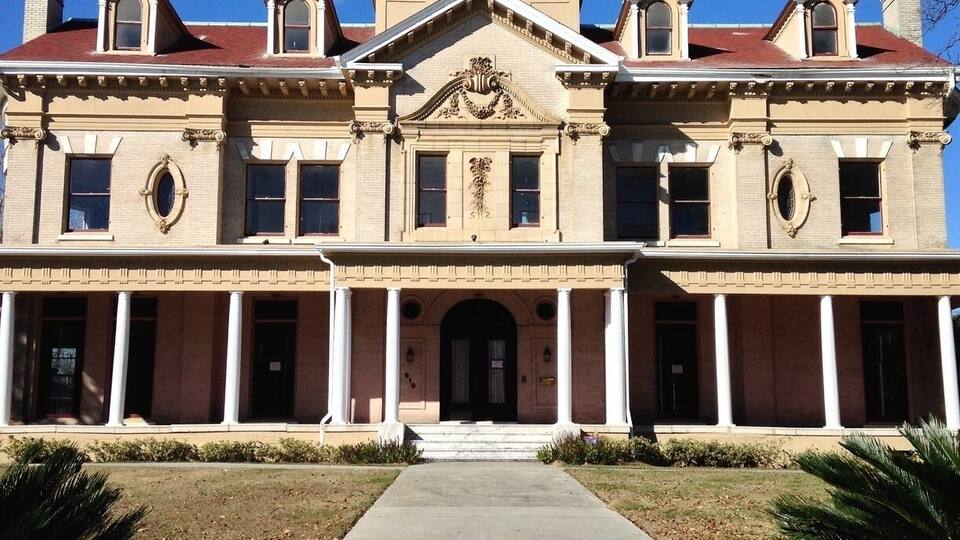 A large, historic building with a symmetrical facade, central pediment, and multiple windows.