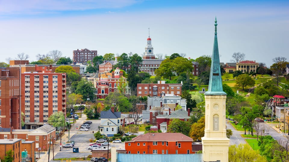 A cityscape with historic buildings, a prominent church steeple, and a large blue building.