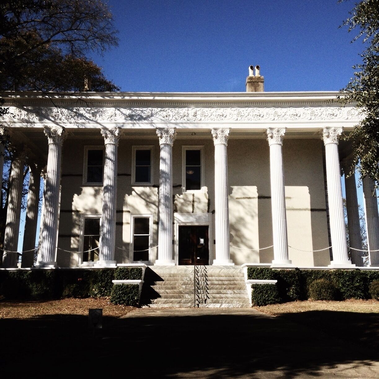 A neoclassical building with a portico of columns, a central entrance, and a symmetrical facade.