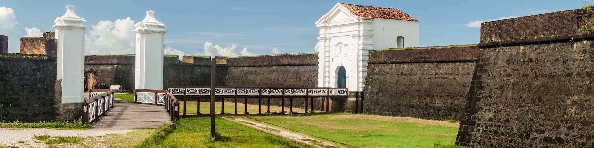 Una fortaleza histórica con torres blancas y un muro de ladrillo.