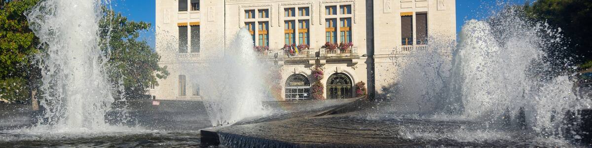 Scenic summer view of central square of Montlucon with Town hall decorated with flowers and fountain in front of entrance, France