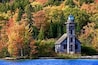Ein Leuchtturm an einer von Bäumen gesäumten Küstenlinie mit Herbstlaub.