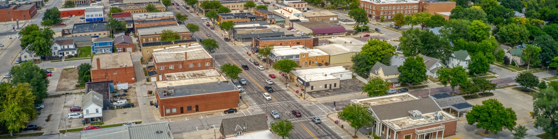 An aerial view of a small town with a grid of streets, various buildings, and surrounding greenery.