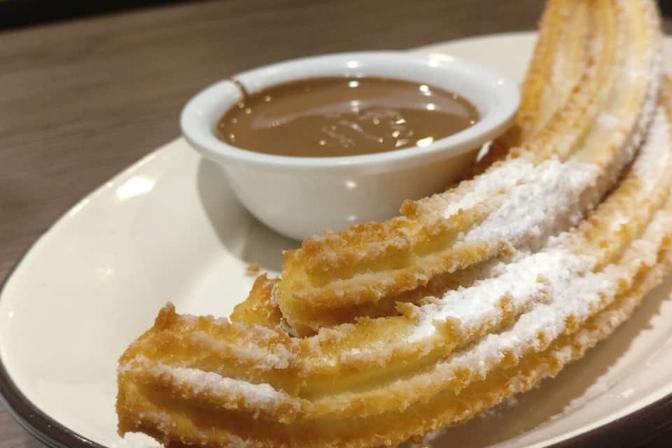 A plate of churros with a dipping sauce.