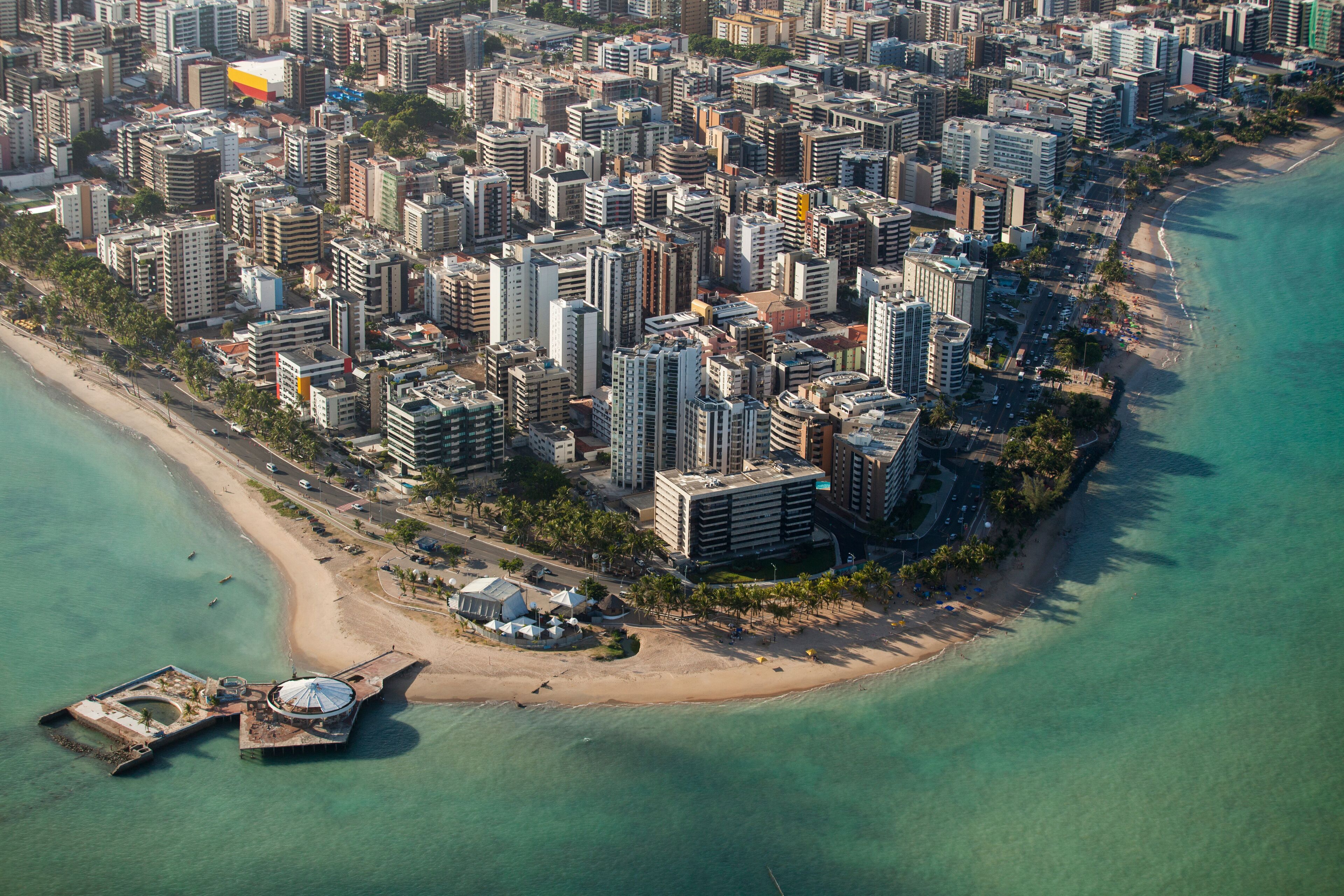 Vista aérea de una ciudad costera con rascacielos, una playa y un puerto deportivo.