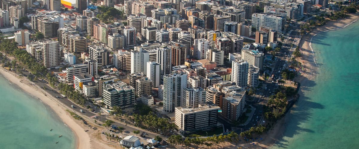 An aerial view of a coastal city with high-rise buildings, a beach, and a marina.